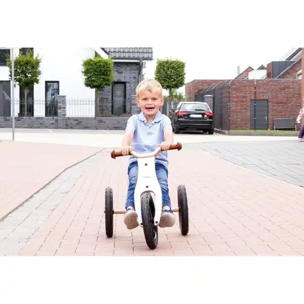 Barn kører på Pinolino Oskar 2-i-1 trehjulet cykel i hvid/natur på en rolig vej.