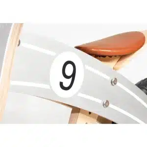 Detaljebillede af Pinolino Nico løbecykel i sølv/natur med brunt sæde og nummer 9 på siden.