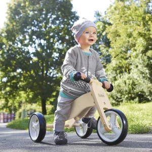 Barn på Pinolino Charlie løbecykel i naturtræ med tre hjul på en sti