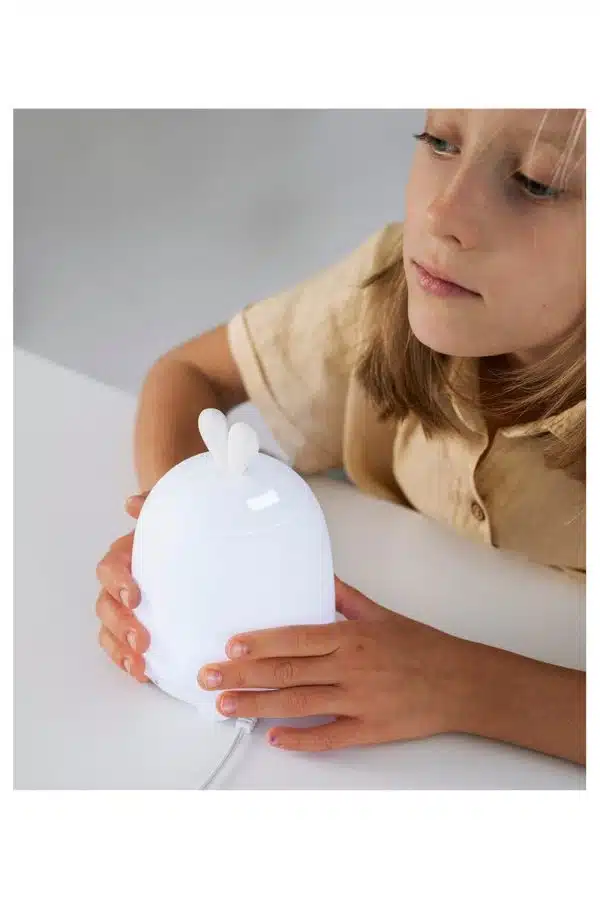Hvid diffuser med kaninører fra Rabbit & Friends på et bord med et barn ved siden af