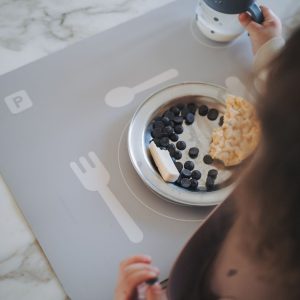 Barn spiser morgenmad på Noui Noui lær at dække bord Grey med omrids til bestik