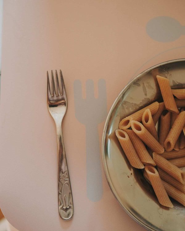Gaffel og tallerken med pasta på Noui Noui læringsdækkeserviet Nude