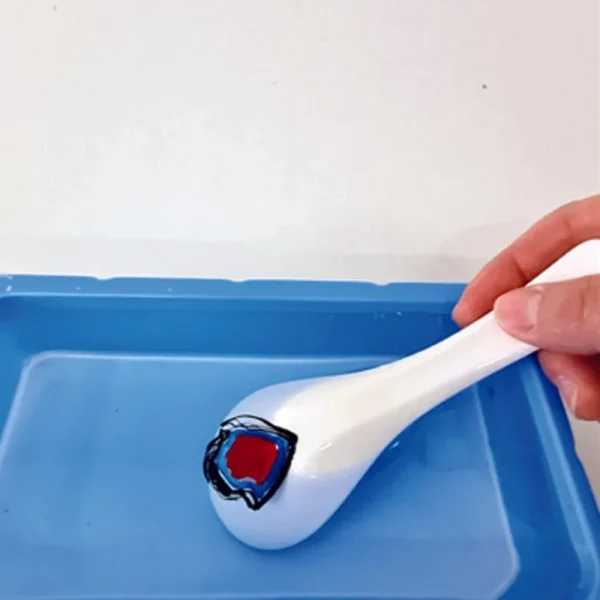 En dekoreret keramisk ske dyppes i en blå bakke med vand – Paw Patrol Floating Art