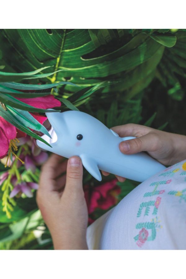 Rabbit & Friends lommelygte Delfinen Bubbly holdt i barnets hænder ved grønne planter