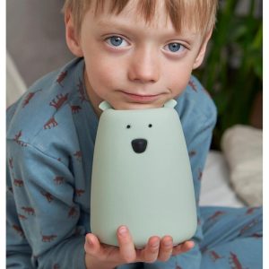 Barn i blå pyjamas holder salviegrøn Store Bjørn natlampe