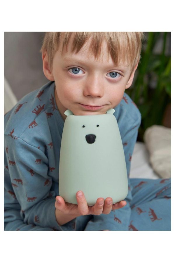 Barn i blå pyjamas holder salviegrøn Store Bjørn natlampe